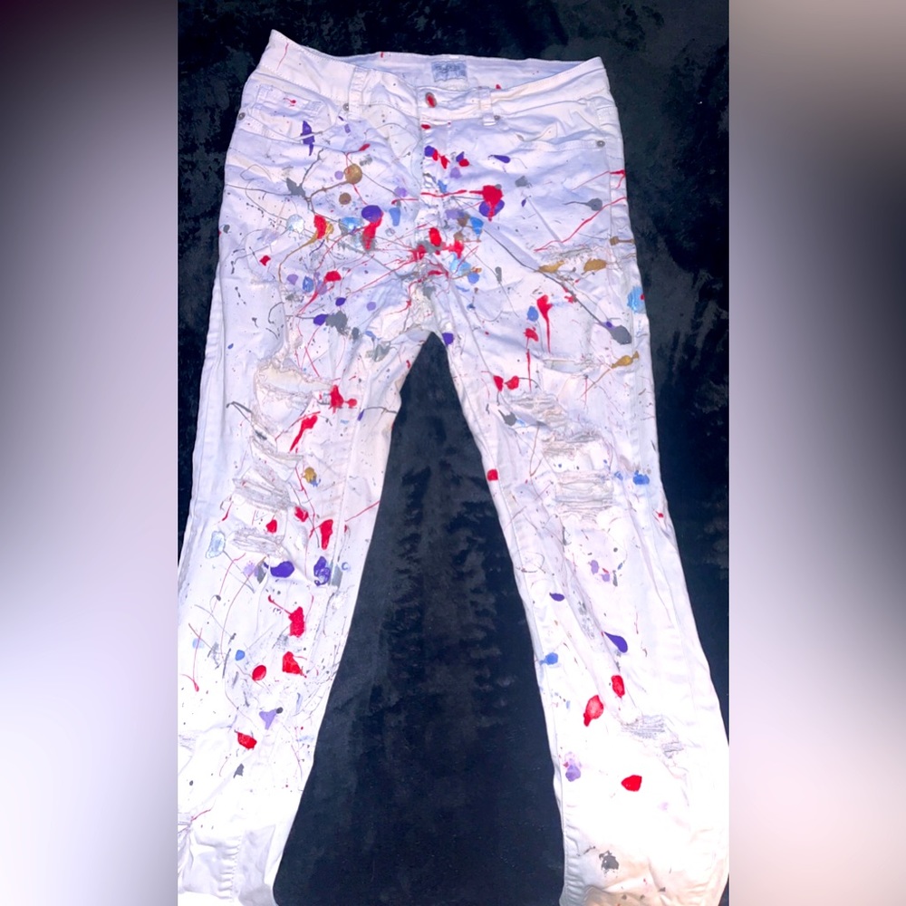 White track 23 jeans that have splatter paint on them.